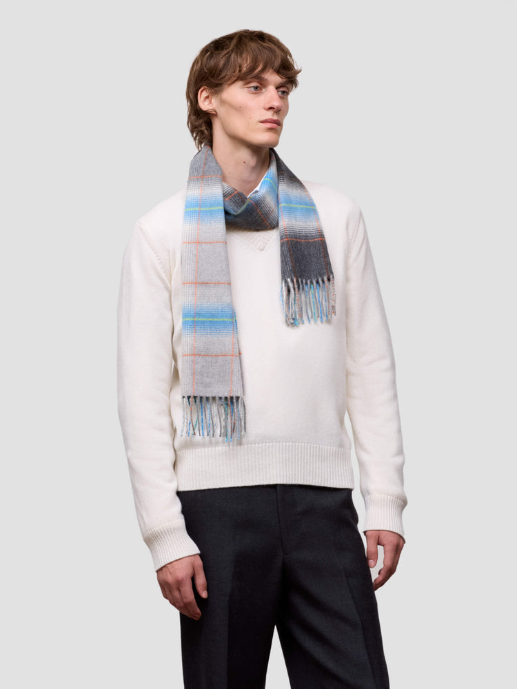 man wearing a white sweater and grey blue checked cashmere scarf on plain background