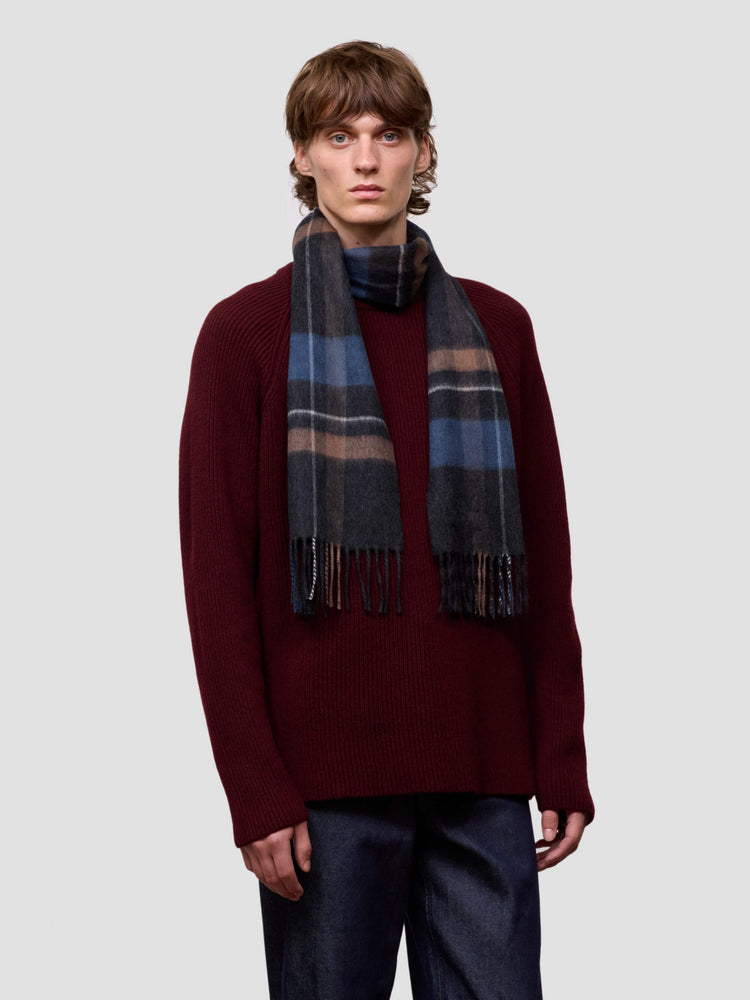 man wearing a burgundy cashmere sweater and checked scarf on a plain background