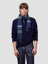 Man wearing a navy sweater and plaid scarf against a light gray background