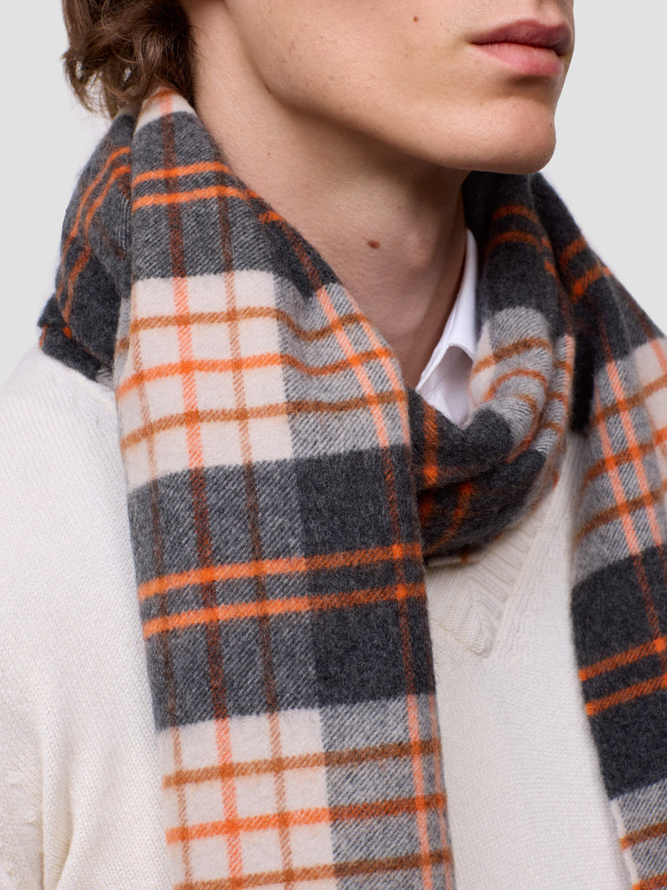 Plaid scarf with orange, gray, and white pattern worn by a man on a plain background