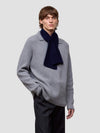 Person wearing a gray sweater with a navy scarf on a light gray background