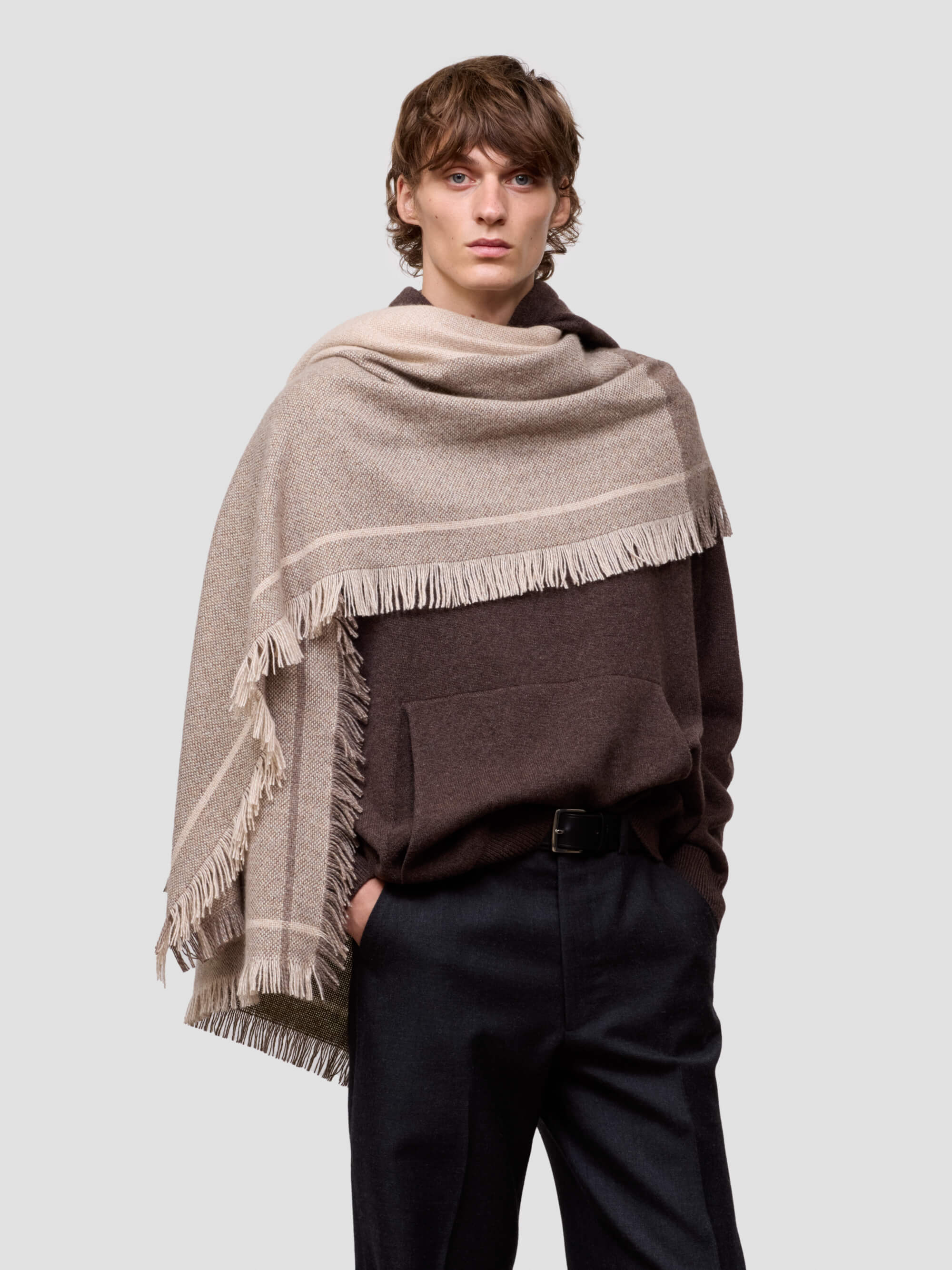 man wearing a beige and brown patterned scarf on a plain background