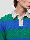 Close-up of a person wearing a green and blue striped sweater with a white collar.