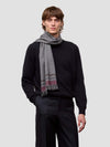 Man wearing a black sweater and gray striped scarf on a light gray background