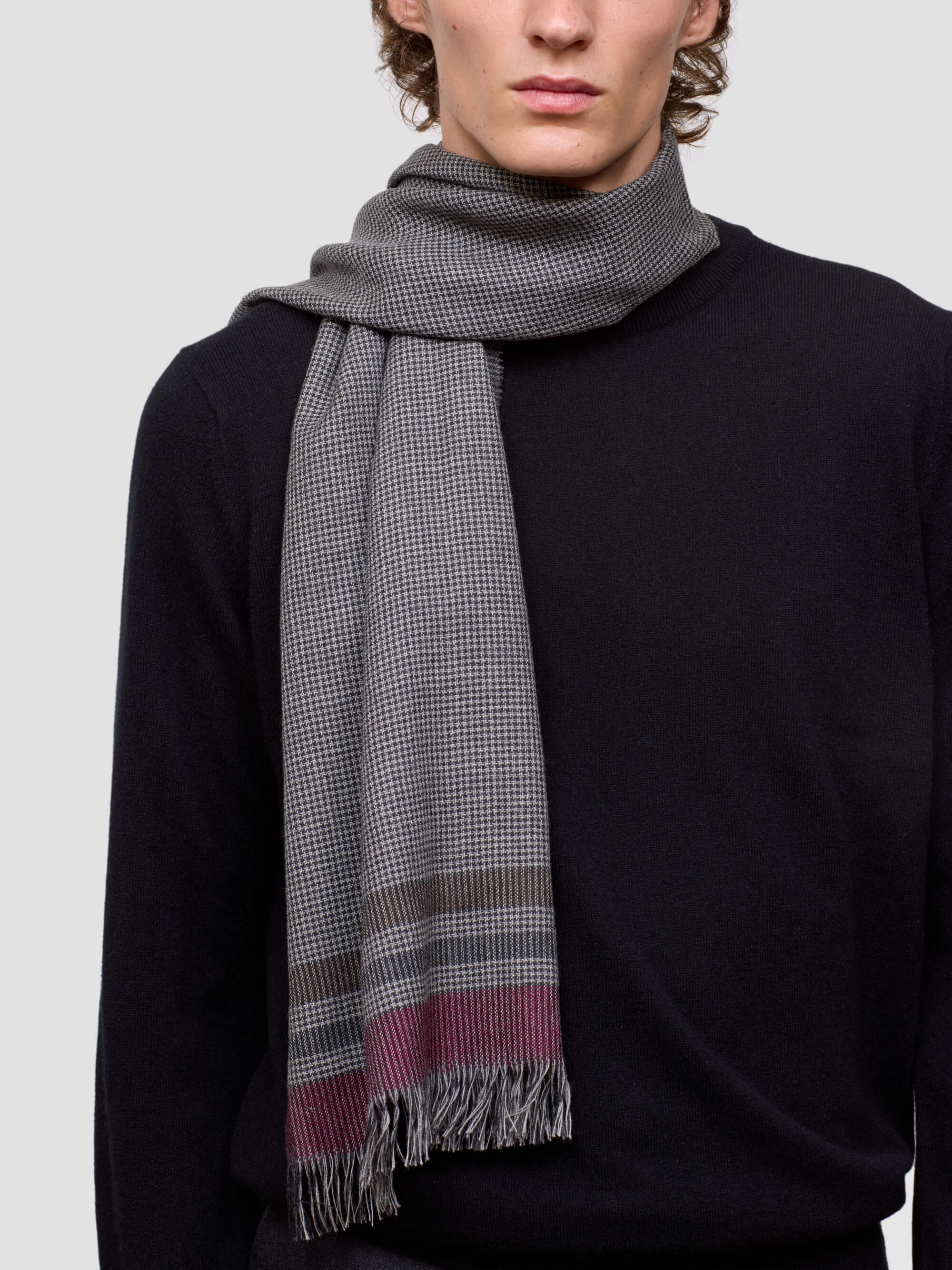 man wearing a gray checkered scarf with a black background