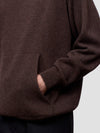 Close-up of a brown cashmere hoodie with a pocket on a light gray background