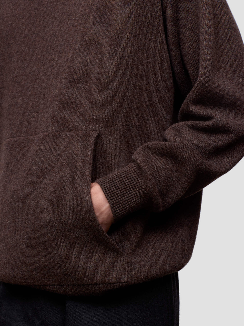 Close-up of a brown cashmere hoodie with a pocket on a light gray background