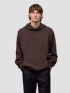 Man wearing a brown hoodie against a light gray background