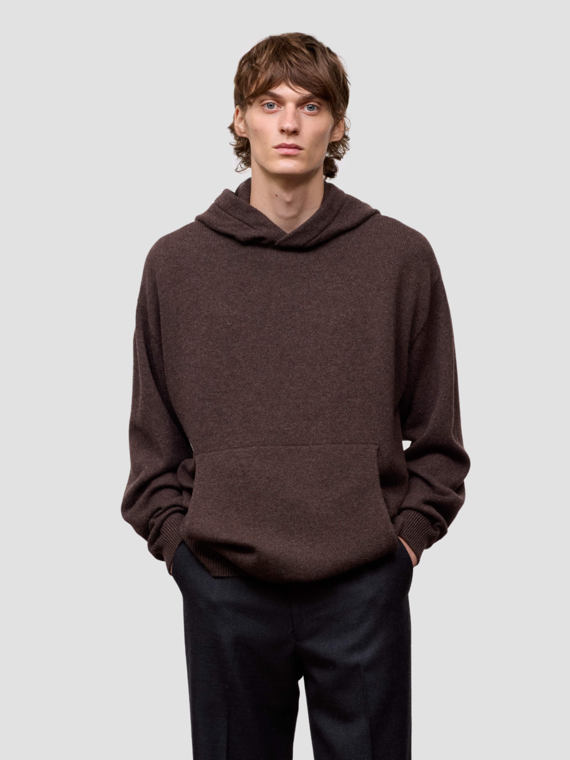 Man wearing a brown hoodie against a light gray background