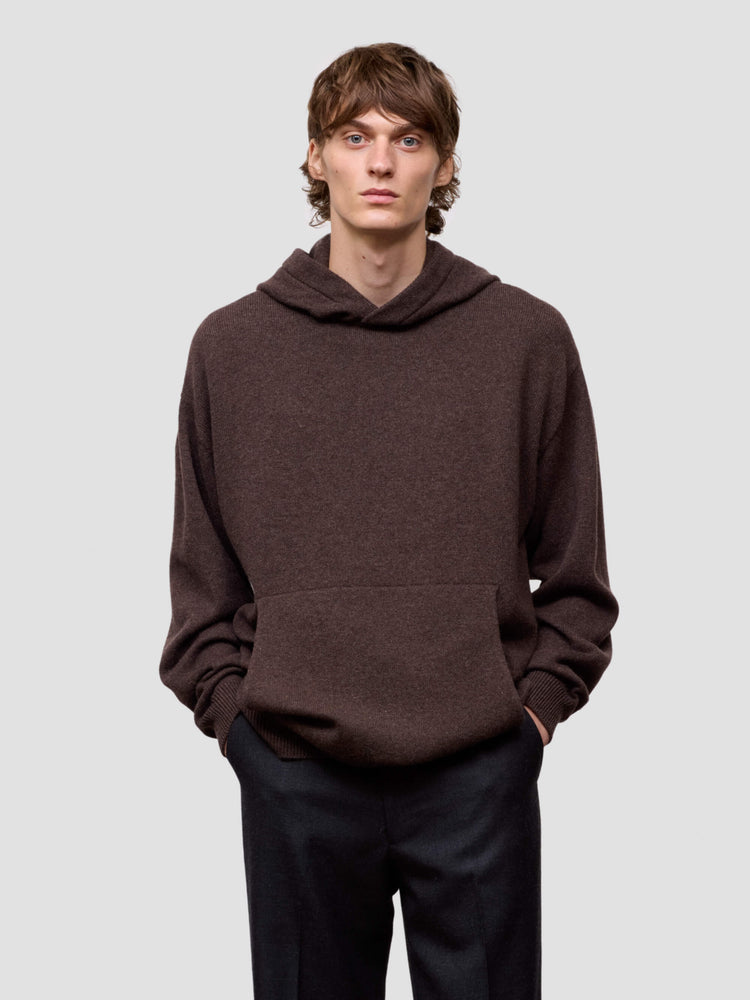 Man wearing a brown hoodie against a light gray background