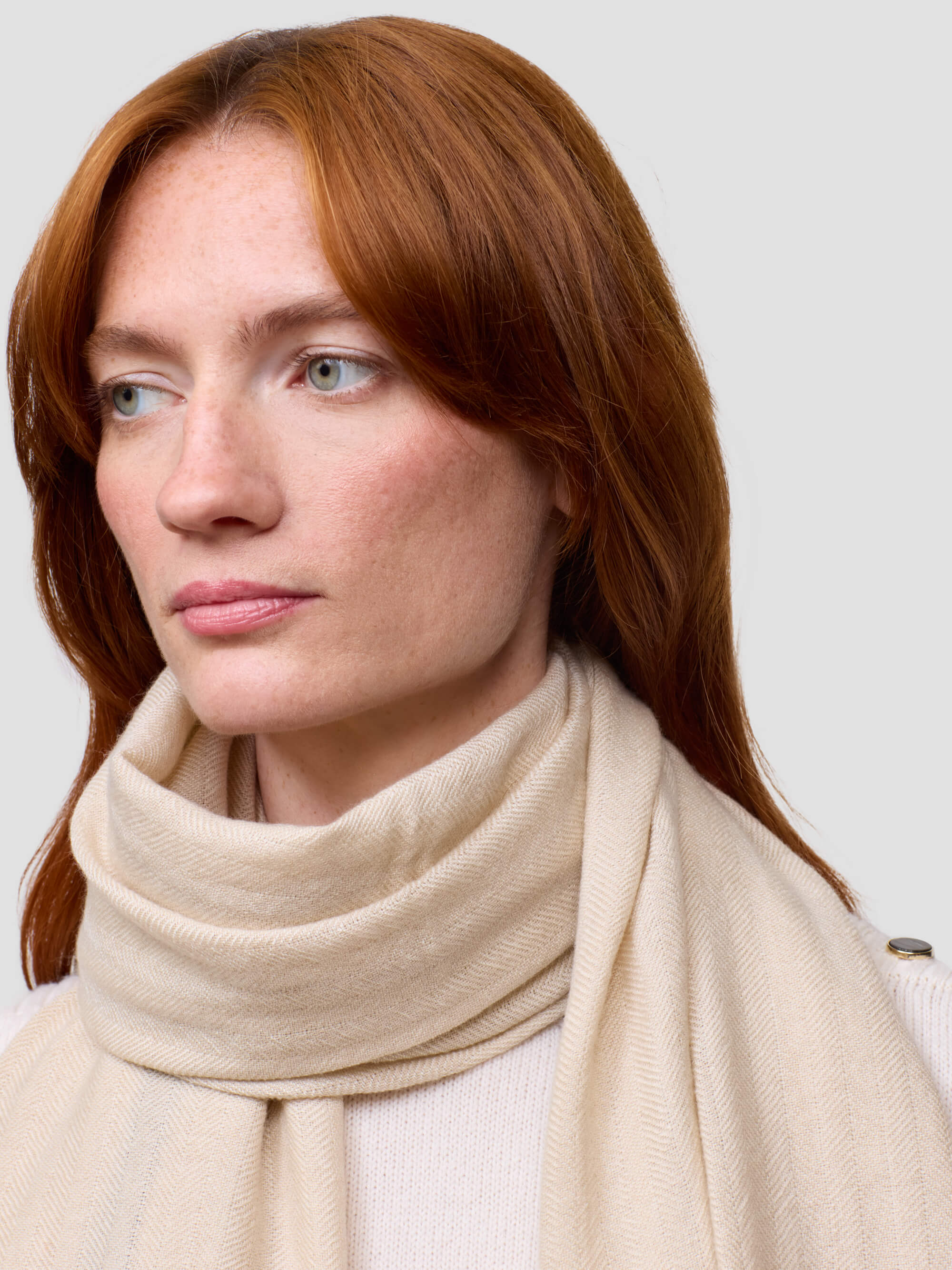 Woman wearing a beige scarf against a plain background