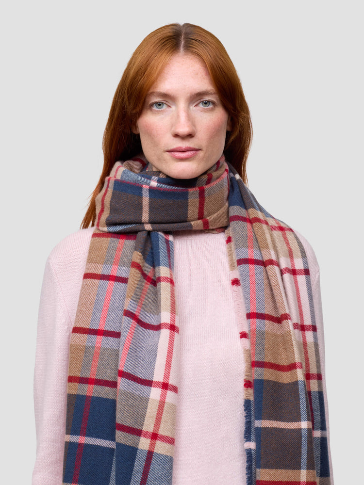 Woman wearing a plaid scarf against a plain background