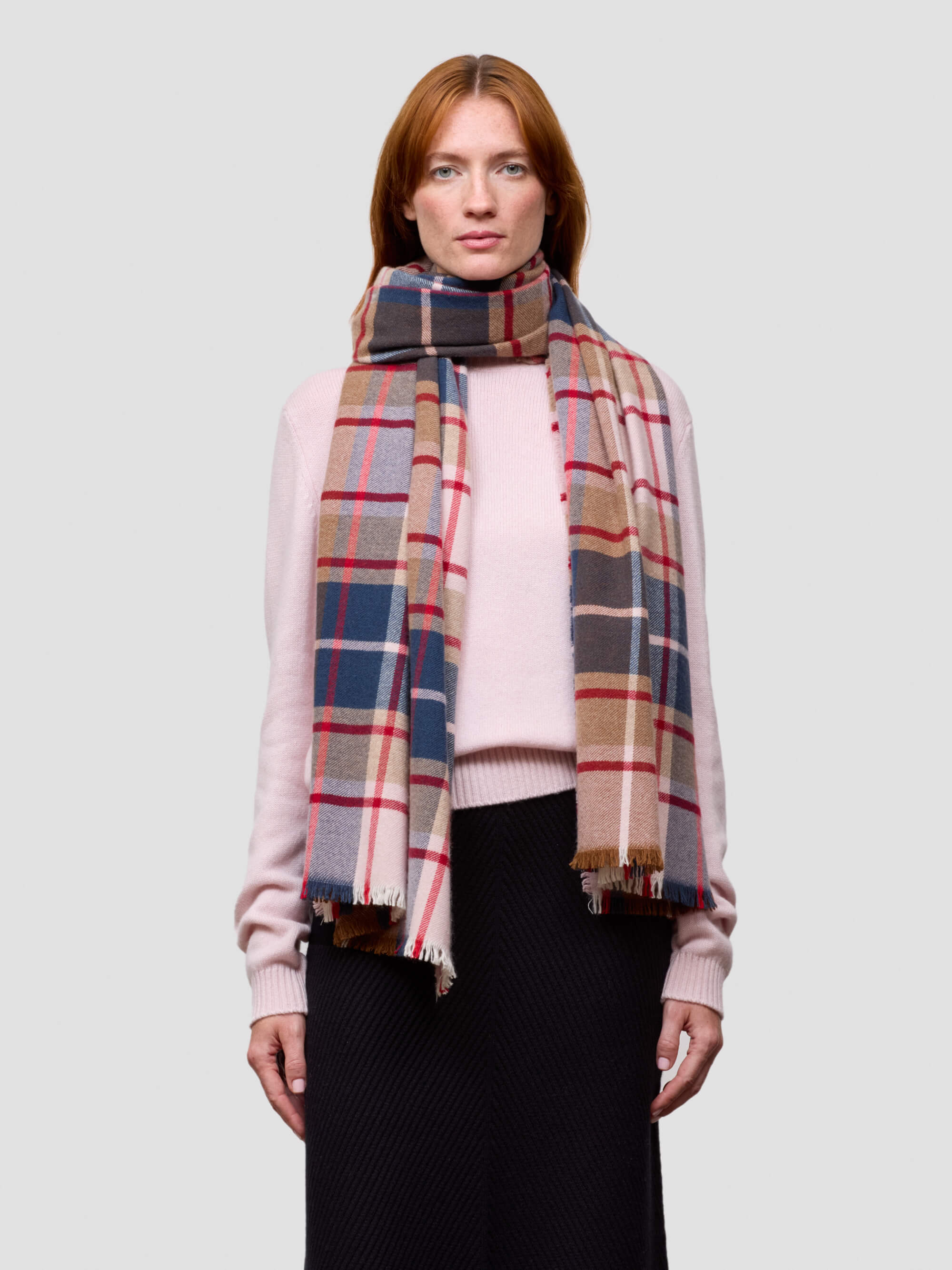 Woman wearing a plaid scarf on a plain background