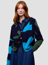 Woman wearing a colorful cardigan with abstract patterns on a plain background