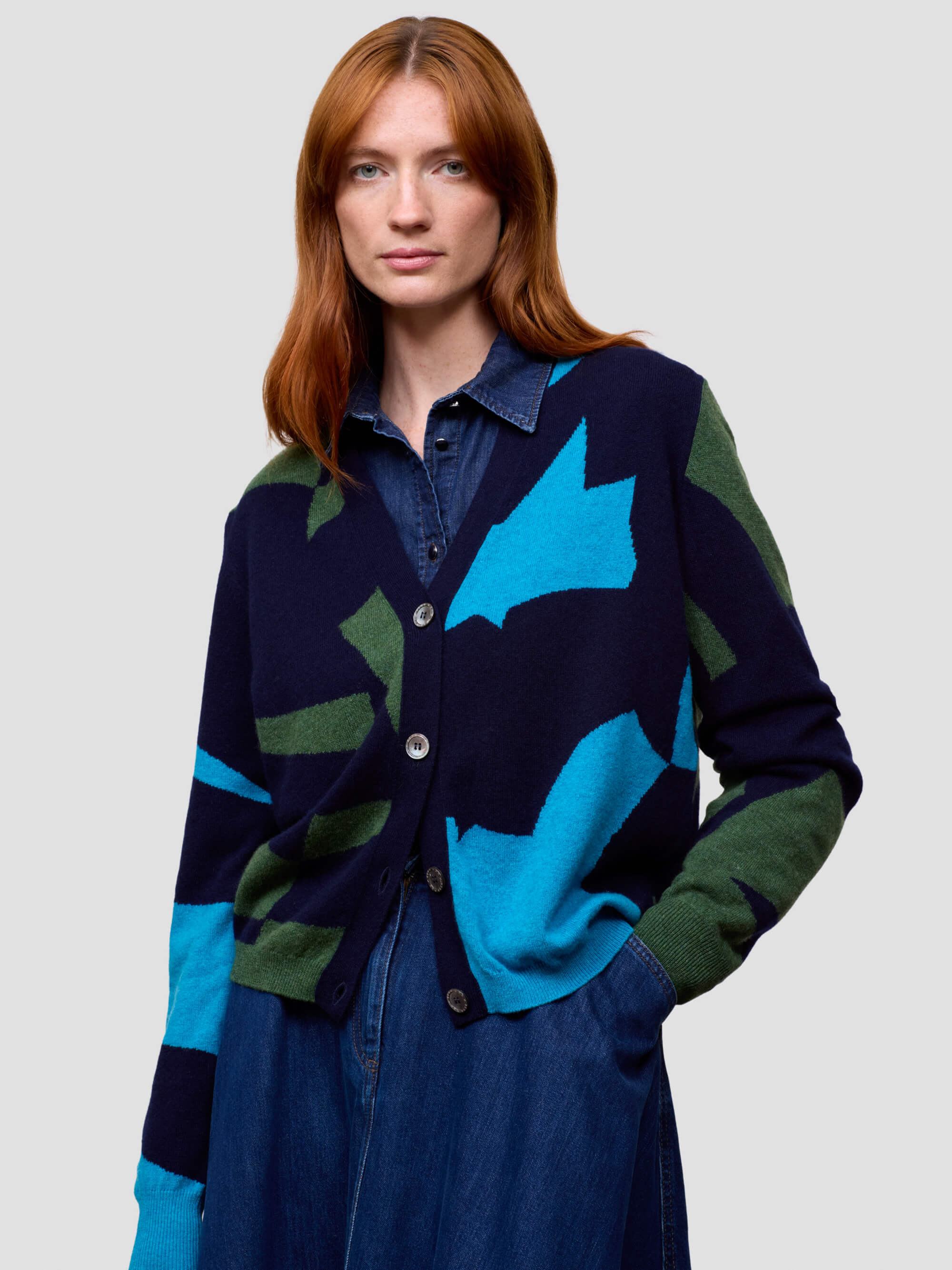 Woman wearing a colorful cardigan with abstract patterns on a plain background
