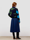 woman wearing a blue coat with a colorful pattern on a white background