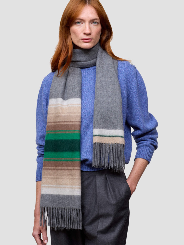 Woman wearing a colorful scarf with a blue sweater on a light gray background